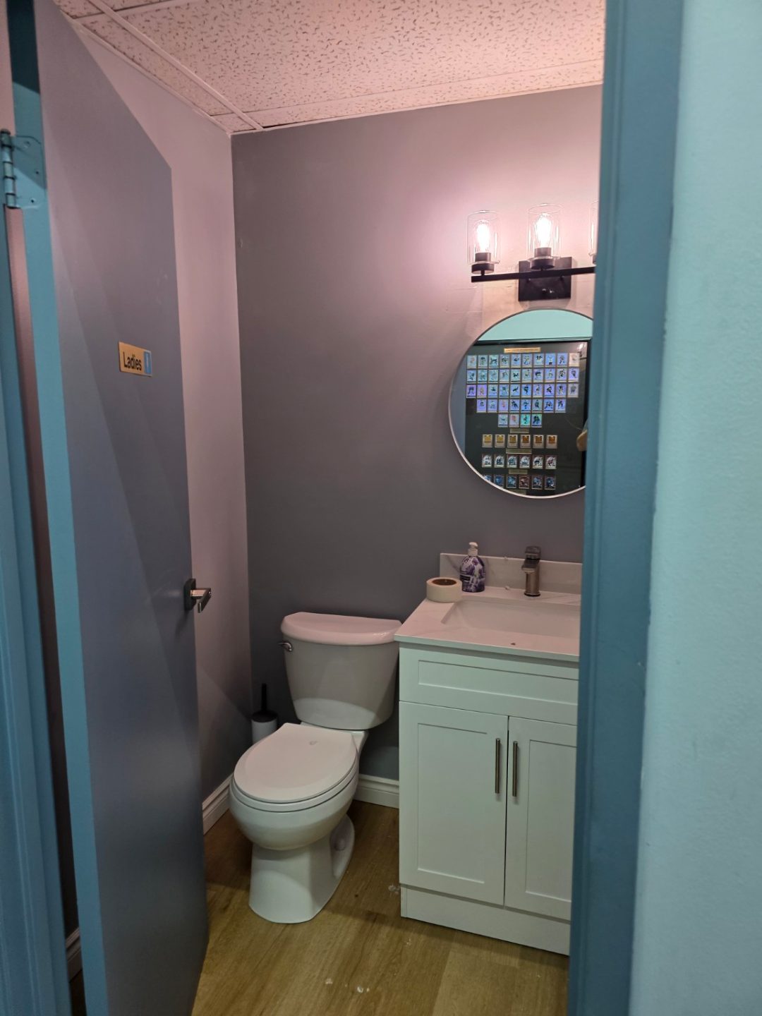 Completed compact employee washroom with vanity, round mirror and toilet