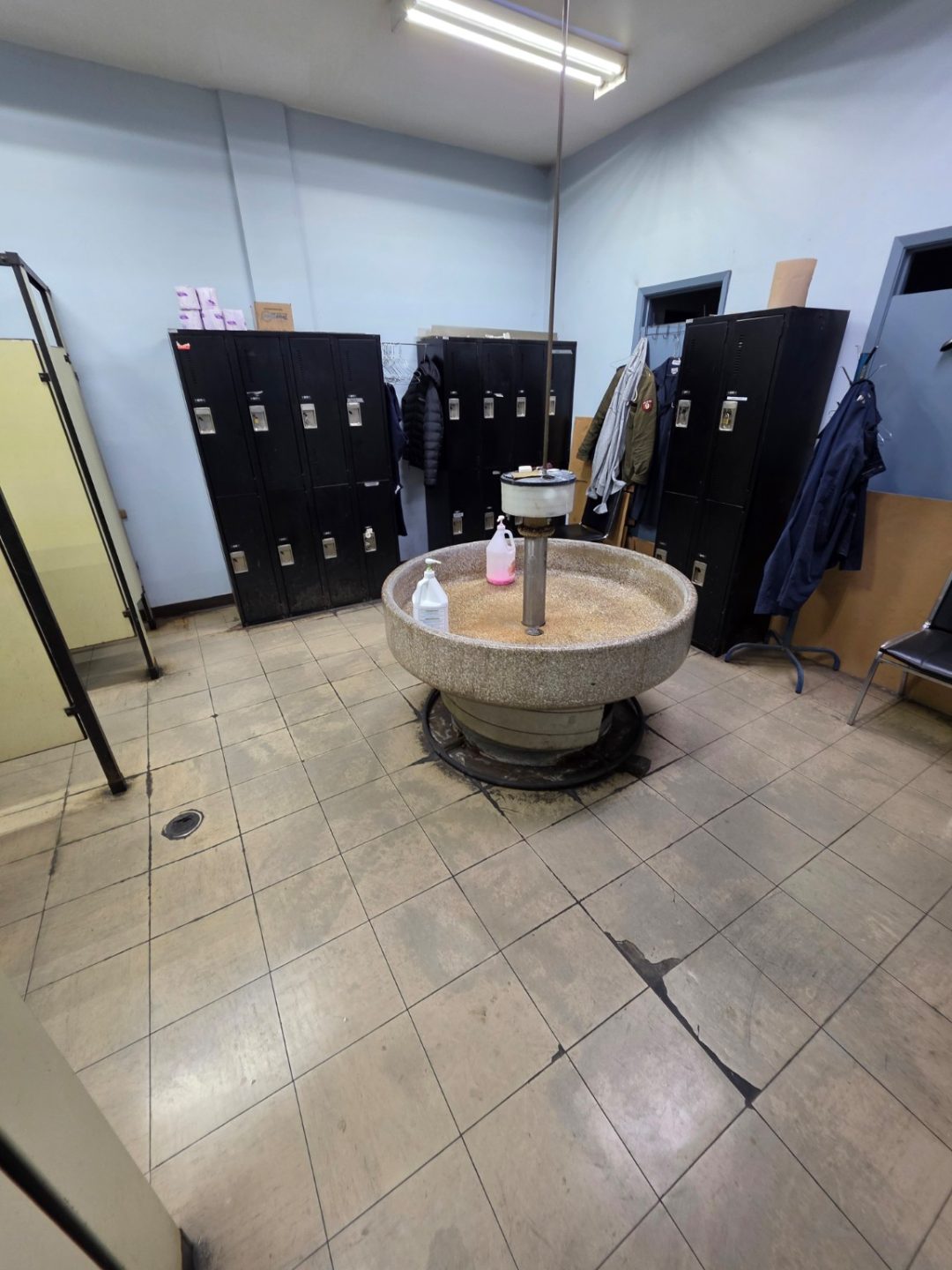 Large employee locker room before renovation with worn tile flooring