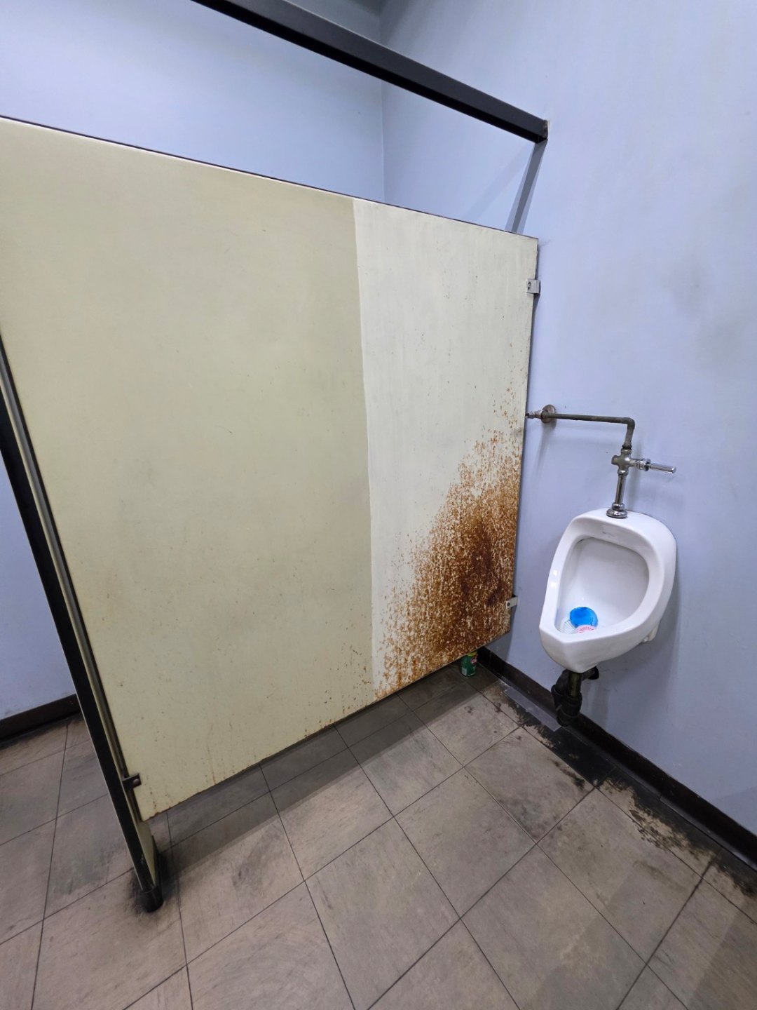 Heavily rusted steel washroom partition before restoration
